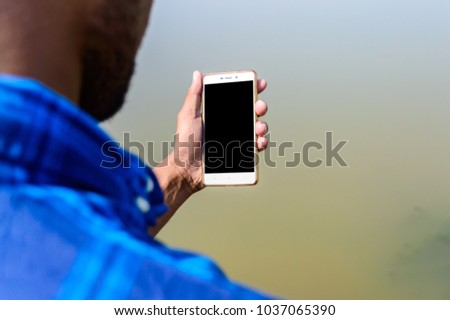 Picture of a person holding his smart phone taken from back side.