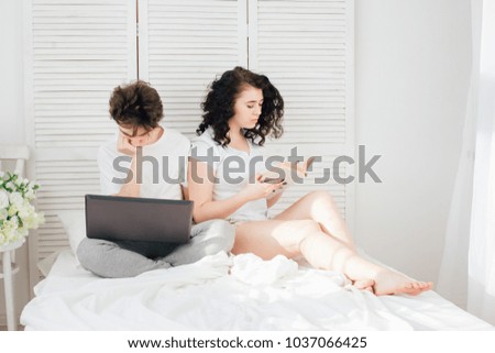 Couple in love in bed in the morning. The guy works for a laptop, the girl reads a book. The concept of love and romance. Toning.