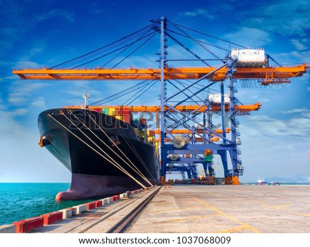 The container vessel  during discharging at an industrial port and move containers to container yard by trucks. Royalty-Free Stock Photo #1037068009
