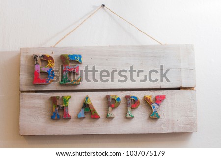 A sign on the wall with the inscription be happy