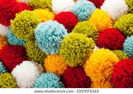 Mat of pompons made from multi-colored handmade yarn
