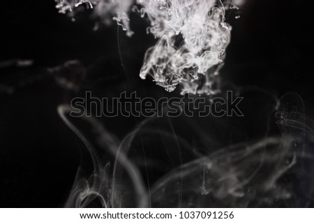 White ink dissolves in water on a black background