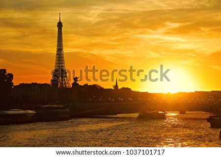 Sunset view of Paris with the Eiffel Tower and the Pont Alexandre III bridge over the river Seine with picturesque sky and a boat moving under the bridge, France