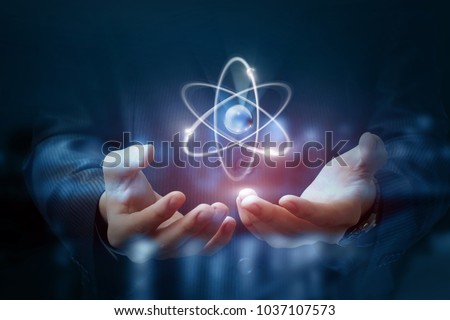 Hands shows the atom on a dark blurred background. Royalty-Free Stock Photo #1037107573