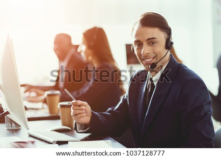 A man of arab appearance works in the call center. He has headphones for talking with customers who call.