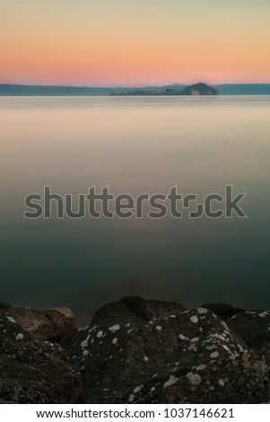 Super long exposure over the Lake in Bolsena, with rocks and still water at sunrise