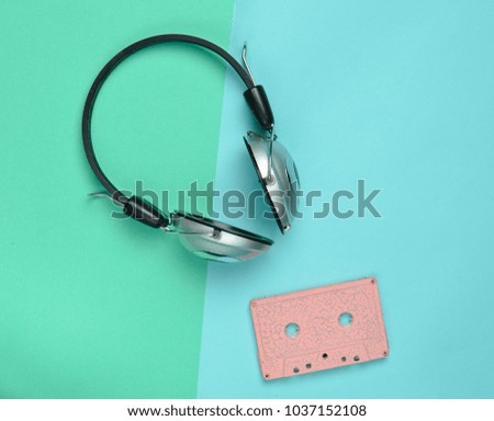 Wireless headphones and audio cassettes on a multicolored pastel paper background. Minimal creative art. Musical retro vibrations. Top view.
