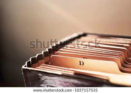 Vintage file folder close up with cinematic sunlight breaking in with the letter "D" on folder tab.