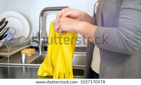 Closeup photo of young woman holding yellow latex gloves