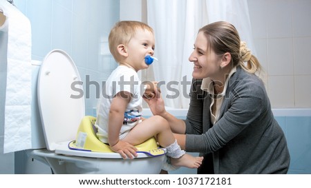 Young mother smiling after her toddler son used toilet Royalty-Free Stock Photo #1037172181