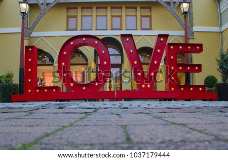 A brightly colored outdoor sculpture consists of red letters spelling LOVE