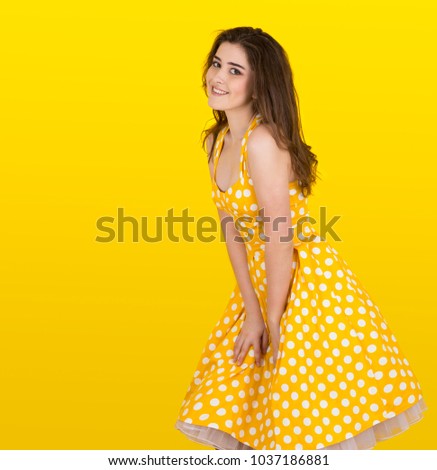 A girl in yellow polka-dress is posing like Marilyn Monroe
