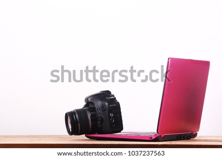 Office table with pink laptop and old dslr camera.