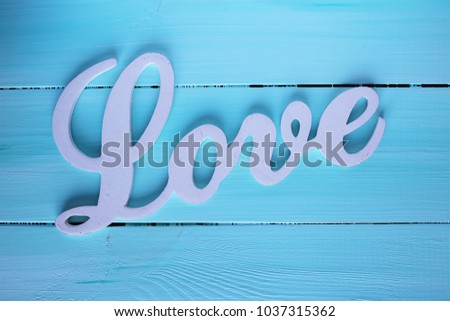 White word LOVE on a blue wooden background