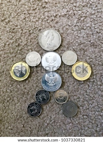 A collection of coins from various Eastern Hemisphere countries, arranged in a stick figure.