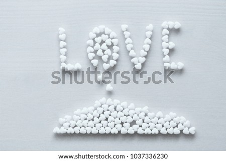 The word love is lined or written from white hearts on a white background. Design with copy space. Top view.