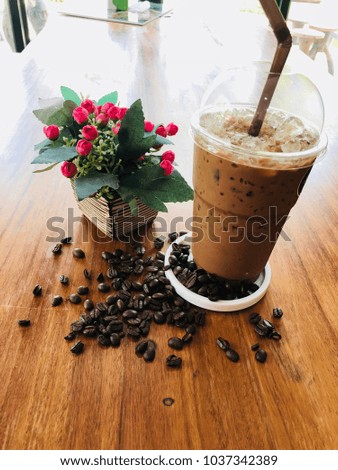 Close up coffee cup, coffee seed and plastic flower on the brown table, selective low key tone