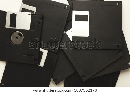 Heap of old black floppy disks on white background. Top view of magnetic retro storage devices, lot of diskettes, copy space