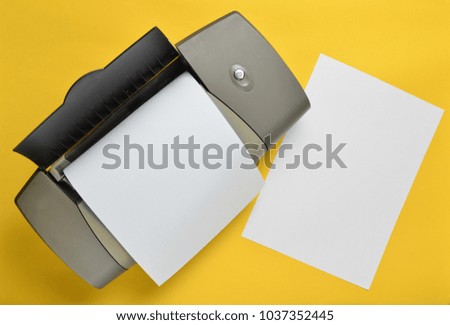 A printer with blank paper forms on a yellow background. Top view, flat lay.
