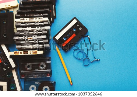 Retro audio cassettes and pencil on blue background. Top view on vintage tapes and simple device for rewinding, copy space. Obsolete technology concept Royalty-Free Stock Photo #1037352646