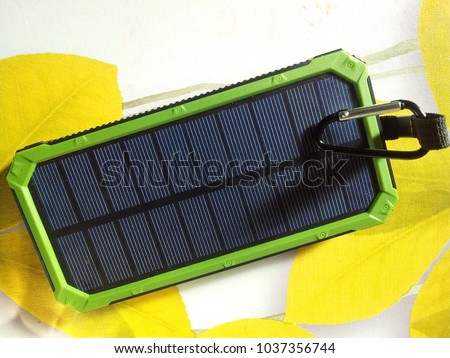 Charger Solar on green background with white USB cord for Charging smartphone phone from the solar battery.