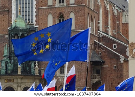 Many flags of European Union, few flags of Poland, waved, in background facade of St. Mary's Cathedral in Krakow, Poland