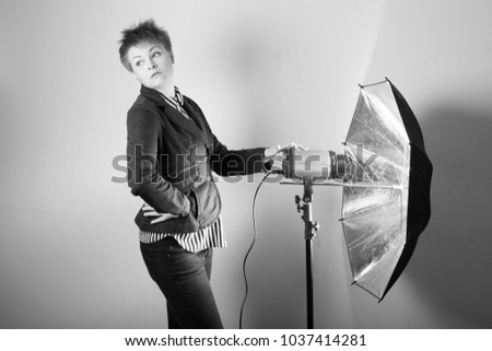 Photographer woman in studio holding photo equipment. Black and white photo