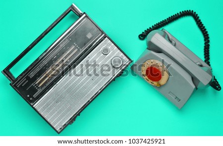 Culture of the 70s. Radio receiver and rotary telephone on blue background. Retro devices. Top view.