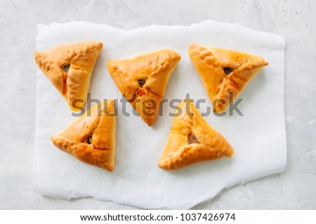 Homemade baked uchpuchmak (samsa) with meat and potato on a white stone background. Top view.