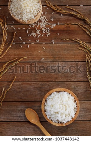 White rice cooked thai jasmine rice in wooden bowl and unmilled rice on wooden background Royalty-Free Stock Photo #1037448142