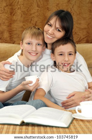 Beautiful charming mama and sons sitting on a brown background