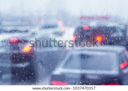 Rain drops on the windshield of the car. View of the traffic jam.