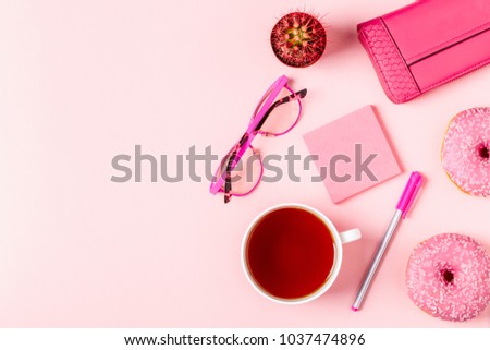 Cup of tea with donuts on a pink pastel background, top view.