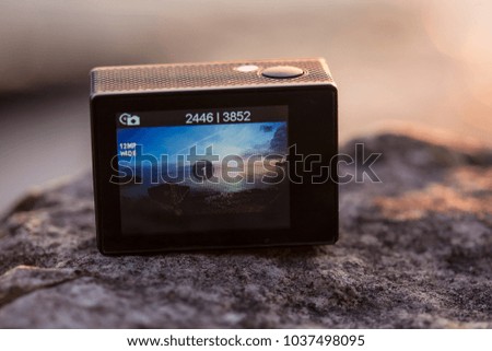 an action camera on a stone taking pictures of a wild lake at sunset/sunrise