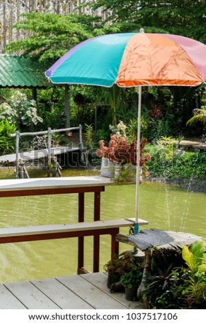 A table, a chair and an umbrella near the pond 