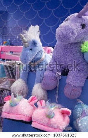 Unicorn slippers and unicorn plush doll displayed on a shelf. With soft focus on the unicorn plush doll.