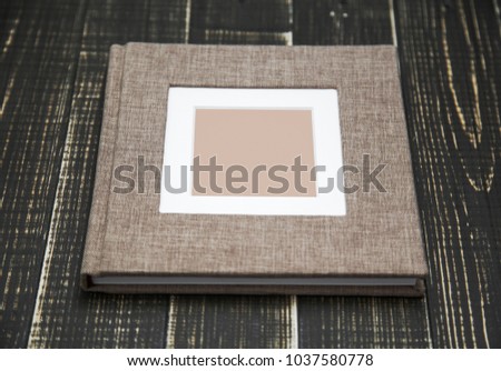 Closeup top view of family photo album isolated on brown wooden background. Horizontal flatlay photography.