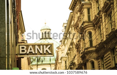 Old-fashioned style image simple bank sign in narrow Vienna street surrounded by traditional European architecture with green dome of St Peter's basilica behind