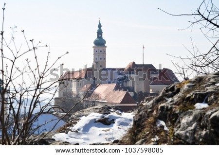 Mikulov castle at the winter covered in snow with smooth light blue sky , south moravia czech republic , touristic destination , view from the 
 kozi hradek  -  Goat hill