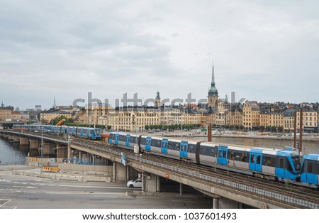                           Blue metro T-Bana trains on the bridge with Gamla Stan island, old city of Stockholm on the background.     