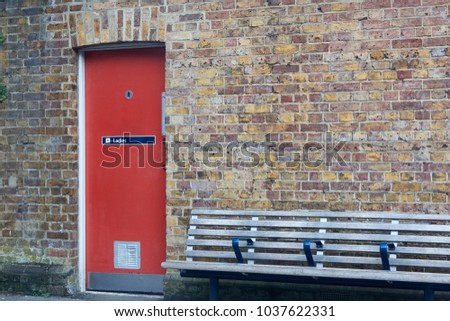Entrance to the women's toilet. Red door in a brick wall.