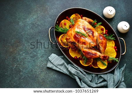 Roasted chicken with oranges ,rosemary and cranberries in a skillet pan.Top view with copy space. Royalty-Free Stock Photo #1037651269