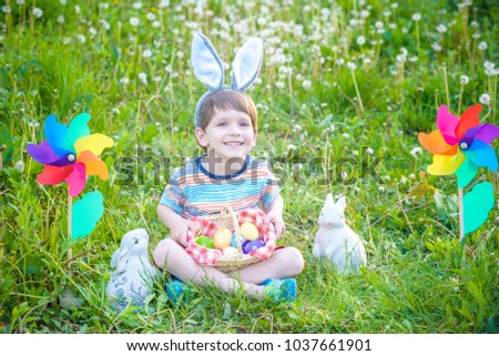 Little boy hunting for Easter egg in spring garden. Cute little child with traditional bunny ears. Smiling happy cute kid having fun on Religious holiday.