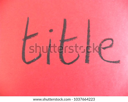 Text title hand written by black oil pastel on red color paper
