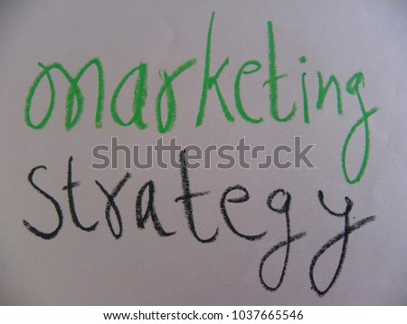 Text marketing strategy written by green and black oil pastel on white color paper