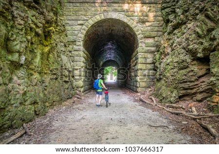 a male cyclist at MKT tunnel  on Katy Trail near Rocheport, Missouri. The Katy Trail is 237 mile bike trail stretching across most of the state of Missouri converted from an old railroad. Royalty-Free Stock Photo #1037666317
