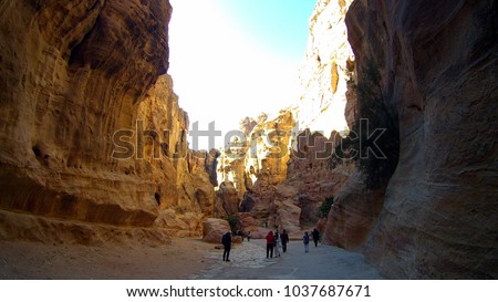 Long curved yellow bent narrow canyon with rock road way and line horizontal rocks wall in mountains near ancient city Petra in Jordan