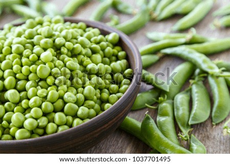 Peeled green peas in a plate on a wooden table. Horisontal photo