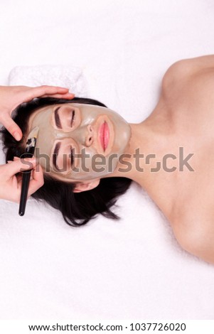 Spa facial mask application. Beautiful relaxed woman having clay face mask in the spa Royalty-Free Stock Photo #1037726020