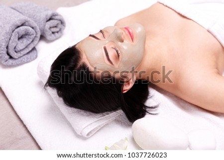Spa facial mask application. Beautiful relaxed woman having clay face mask in the spa Royalty-Free Stock Photo #1037726023